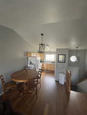 Dining room featuring dark wood-type flooring, vaulted ceiling, and a textured ceiling