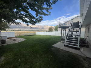 View of yard with an outdoor fire pit, a deck with mountain view, and a trampoline