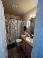 Full bathroom featuring shower / tub combo with curtain, a textured ceiling, vanity, and toilet