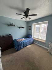 Carpeted bedroom with a textured ceiling and ceiling fan