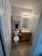 Bathroom with vanity, toilet, a textured ceiling, and tile patterned floors