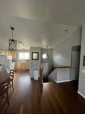 Interior space with vaulted ceiling, a textured ceiling, and dark hardwood / wood-style flooring