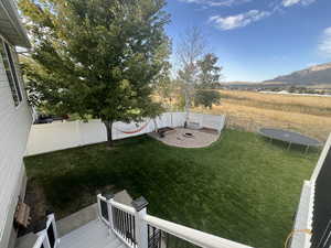 View of yard featuring a deck with mountain view and a trampoline