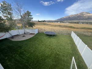 View of yard featuring a trampoline, a rural view, and a mountain view