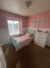 Bedroom featuring dark carpet and a textured ceiling