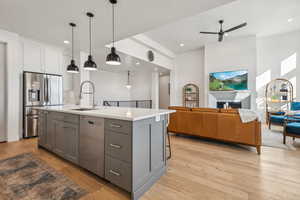 Kitchen featuring gray cabinets, a center island with sink, stainless steel appliances, and white cabinets