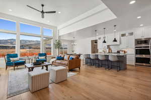 Living room with ceiling fan and large windows with mountain views