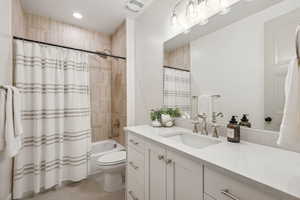 Full bathroom with shower / tub combo with curtain, tile patterned flooring, vanity, and toilet