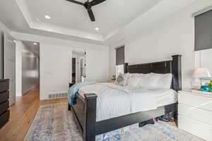 Bedroom featuring ceiling fan, light wood-type flooring, and a raised ceiling