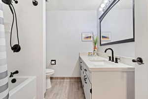 Full bathroom with vanity, toilet, shower / bath combo, and hardwood / wood-style flooring