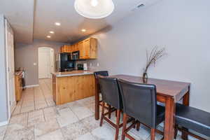 Kitchen featuring kitchen peninsula, light brown cabinetry, light tile patterned floors, and stainless steel appliances