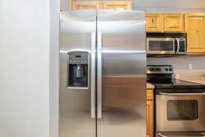 Kitchen featuring light brown cabinetry and appliances with stainless steel finishes