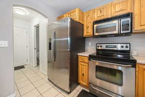 Kitchen featuring light brown cabinetry, light tile patterned floors, and appliances with stainless steel finishes