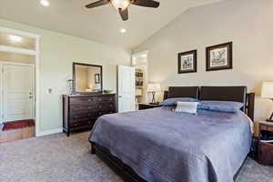 Carpeted bedroom with lofted ceiling and ceiling fan