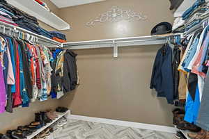 Walk in closet with light parquet flooring