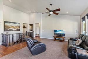 Living room featuring ceiling fan, hardwood / wood-style flooring, and high vaulted ceiling