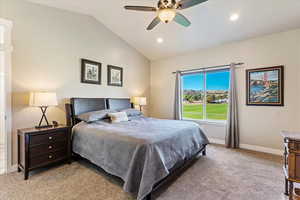 Carpeted bedroom featuring ceiling fan and lofted ceiling