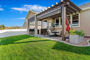 Back of house with a pergola, a patio area, and a lawn