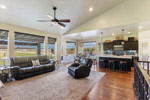 Living room with dark hardwood / wood-style floors, high vaulted ceiling, sink, and ceiling fan