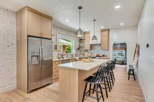 Kitchen with light hardwood / wood-style flooring, stainless steel appliances, a center island, and light brown cabinetry