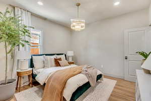 Bedroom with light hardwood / wood-style flooring and a chandelier