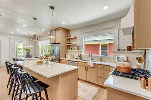 Kitchen featuring appliances with stainless steel finishes, light hardwood / wood-style floors, a kitchen island, light brown cabinetry, and sink