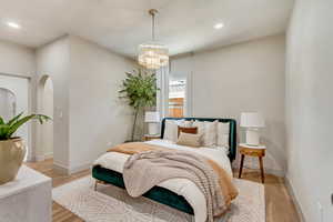 Bedroom with an inviting chandelier and light wood-type flooring