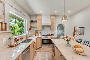 Kitchen featuring light brown cabinetry, light stone countertops, stainless steel appliances, and sink