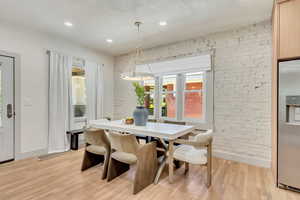 Dining area featuring brick wall and light hardwood / wood-style flooring