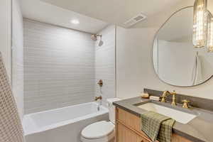 Full bathroom with tiled shower / bath combo, vanity, and toilet