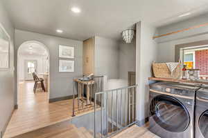 Washroom with separate washer and dryer and light hardwood / wood-style floors