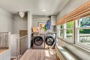 Laundry room featuring light hardwood / wood-style flooring, plenty of natural light, and washing machine and dryer