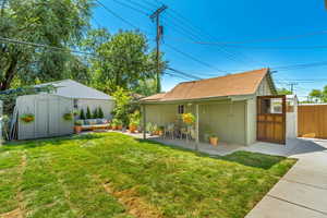 Rear view of property featuring a storage shed, a patio, and a yard