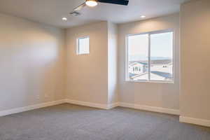 Unfurnished room with plenty of natural light, ceiling fan, and carpet flooring