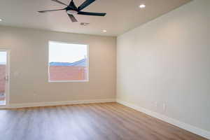 Empty room with ceiling fan and light wood-type flooring