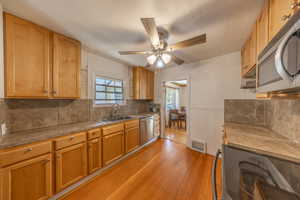 Kitchen featuring ceiling fan, sink, tasteful backsplash, appliances with stainless steel finishes, and light hardwood / wood-style floors