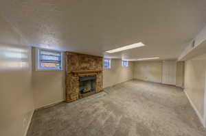 Basement with light colored carpet, a textured ceiling, and a wealth of natural light