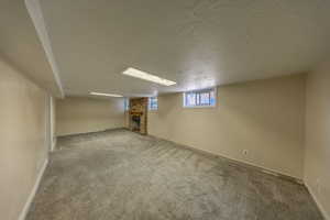 Basement with a textured ceiling, a fireplace, and light colored carpet