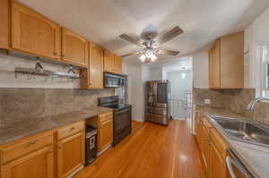 Kitchen with ceiling fan, decorative backsplash, sink, light hardwood / wood-style floors, and appliances with stainless steel finishes