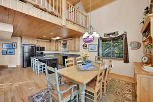 Dining room with light hardwood / wood-style floors, wood ceiling, vaulted ceiling, and an inviting chandelier