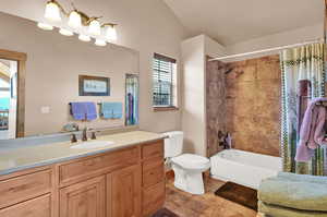 Full bathroom featuring vanity, lofted ceiling, tile patterned floors, toilet, and shower / tub combo with curtain