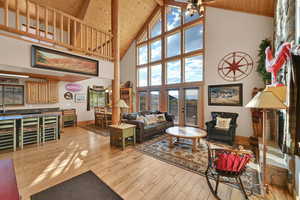 Living room with light wood-type flooring, beam ceiling, wood ceiling, sink, and high vaulted ceiling