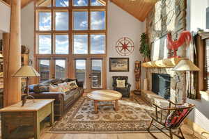 Living room with light wood-type flooring, high vaulted ceiling, a fireplace, and wooden ceiling