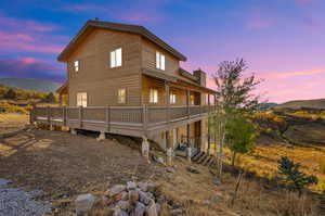 Back house at dusk with a deck with mountain view