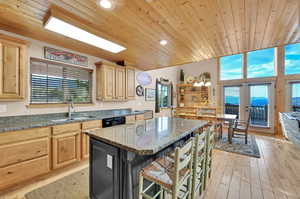 Kitchen featuring light hardwood / wood-style floors, a breakfast bar, sink, hanging light fixtures, and a center island