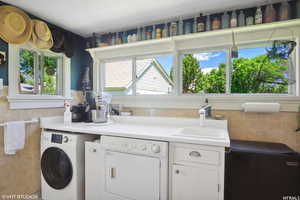 Washroom featuring tile walls, sink, and washing machine and clothes dryer