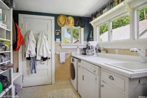 Laundry room with separate washer and dryer, tile walls, and sink