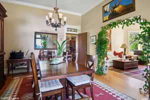 Dining space featuring hardwood / wood-style flooring, crown molding, and an inviting chandelier