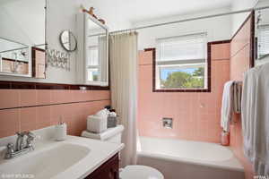 Full bathroom featuring vanity, shower / bath combo with shower curtain, toilet, and a healthy amount of sunlight