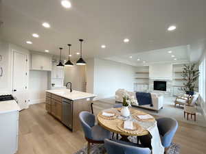 Kitchen featuring pendant lighting, sink, white cabinetry, a center island with sink, and stainless steel dishwasher